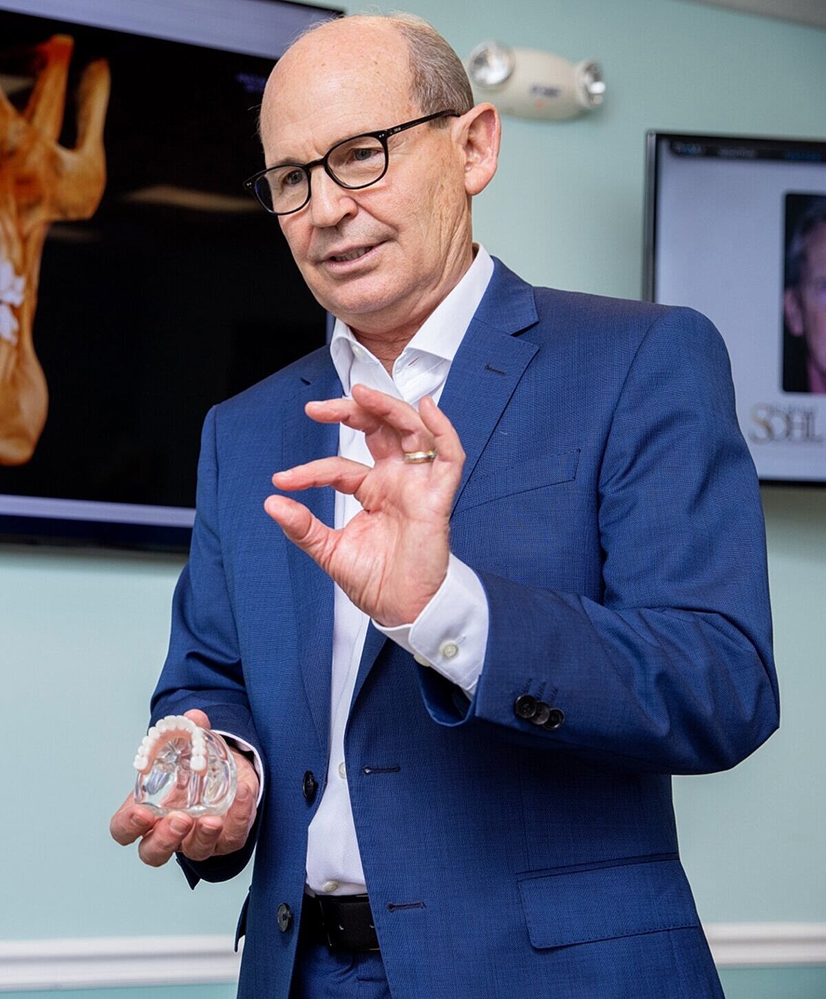 Person demonstrating dental model in professional setting.