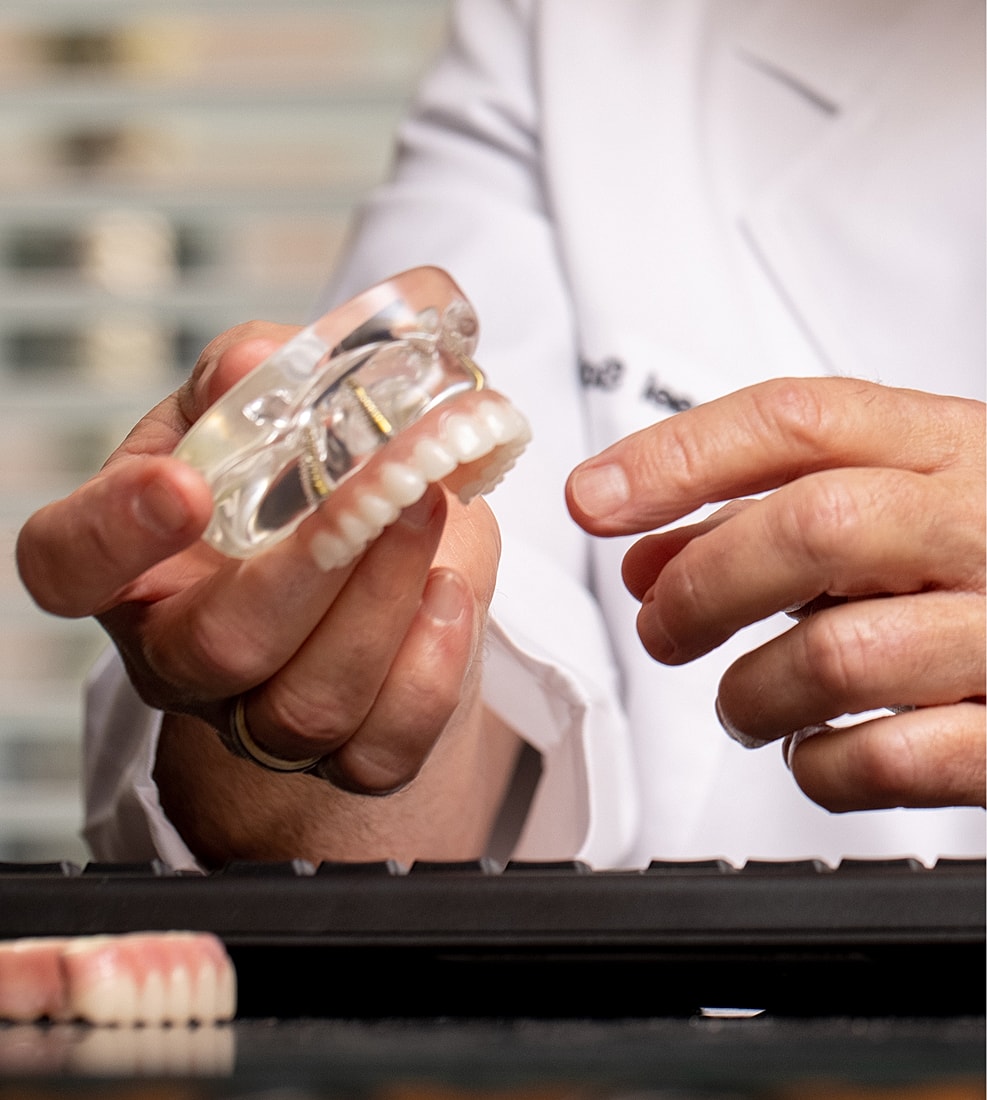 Older man discussing dental models with another person.