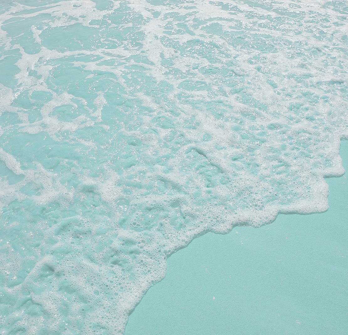 Gentle waves on a turquoise sandy beach.