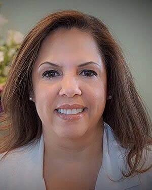 Smiling woman with long hair and white attire.