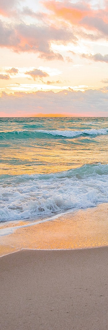 Sunset over waves on a tranquil beach.