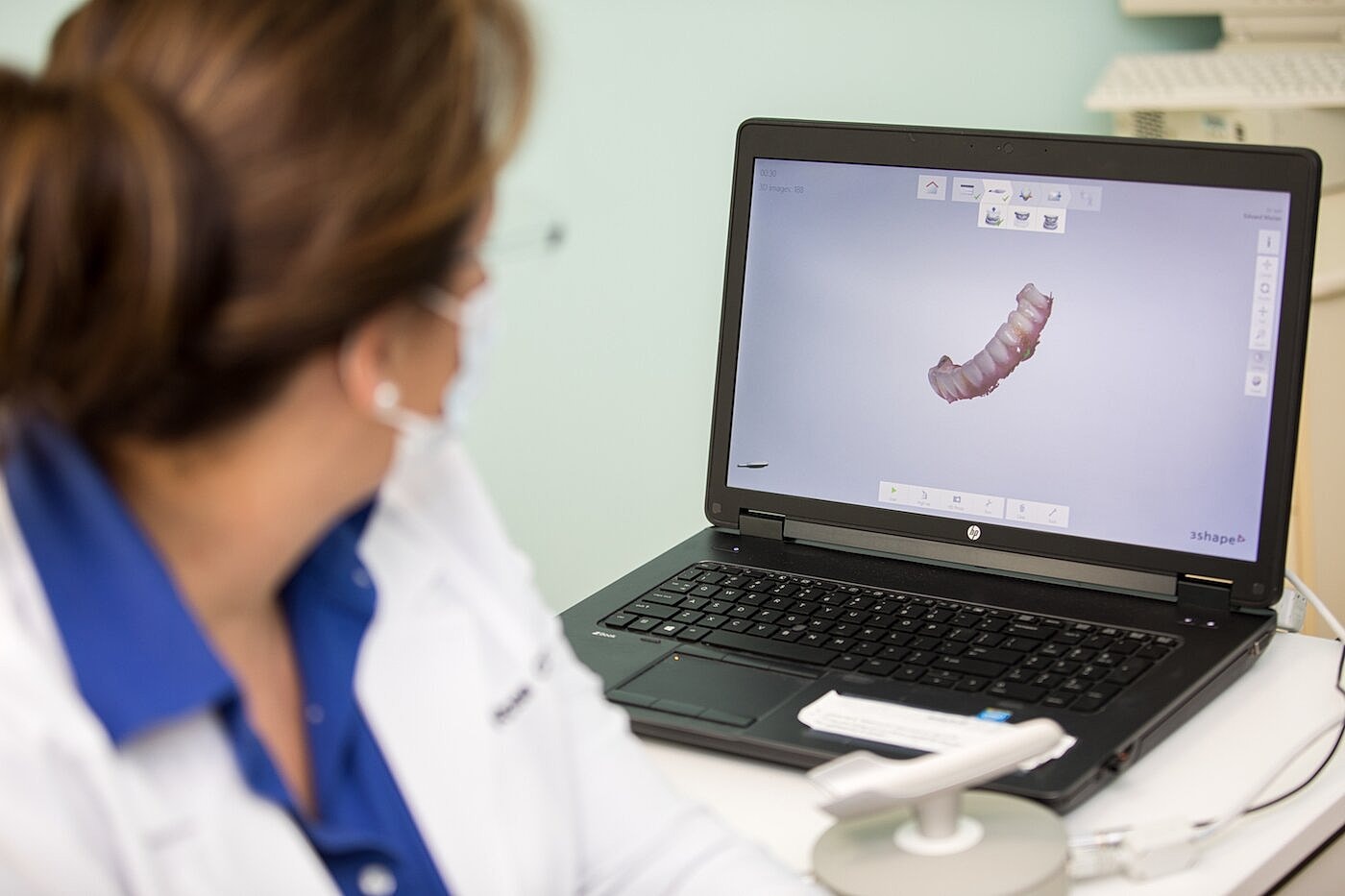 Dental professional viewing 3D model on laptop.