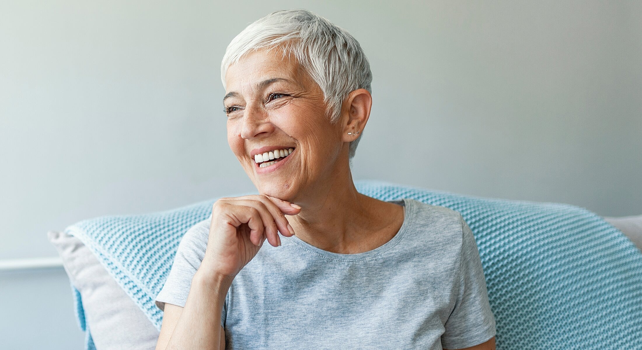 Smiling elderly woman sitting on couch.