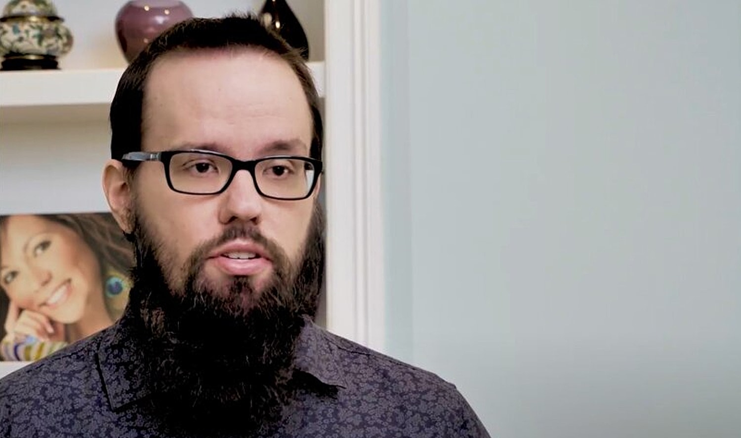 Man in a cowboy hat smiling warmly indoors.
